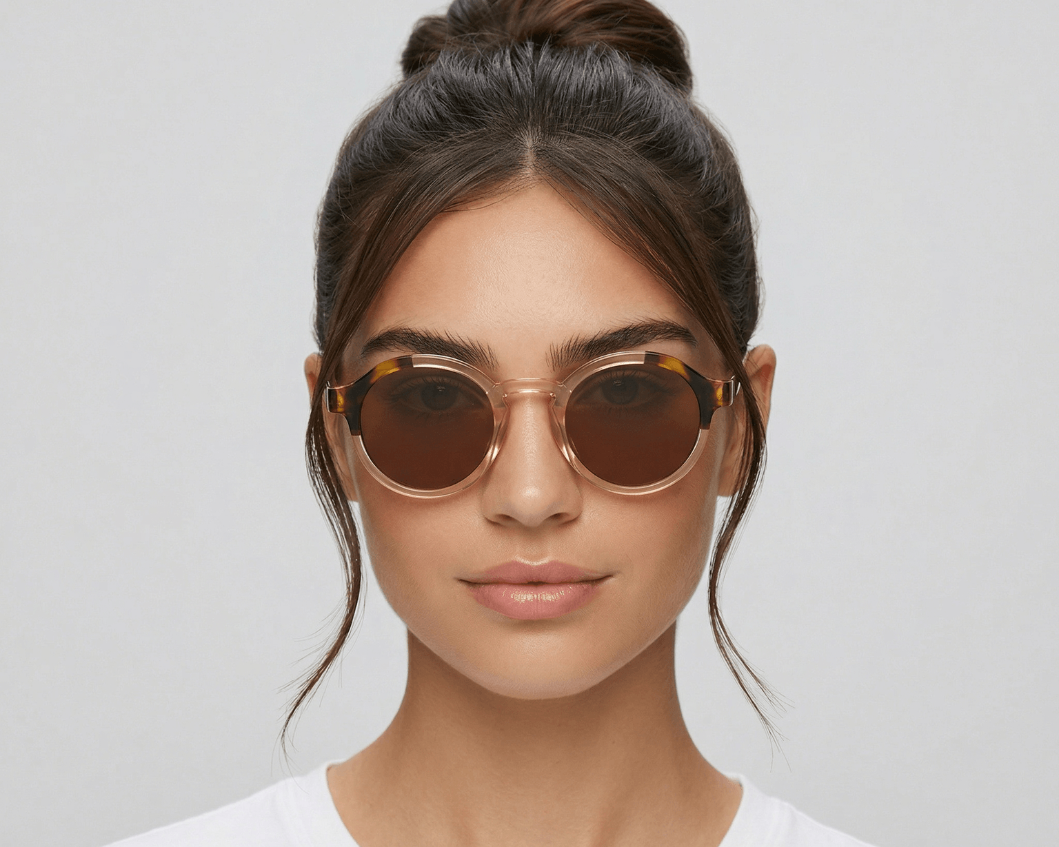 Woman wearing round sunglasses with a plain background
