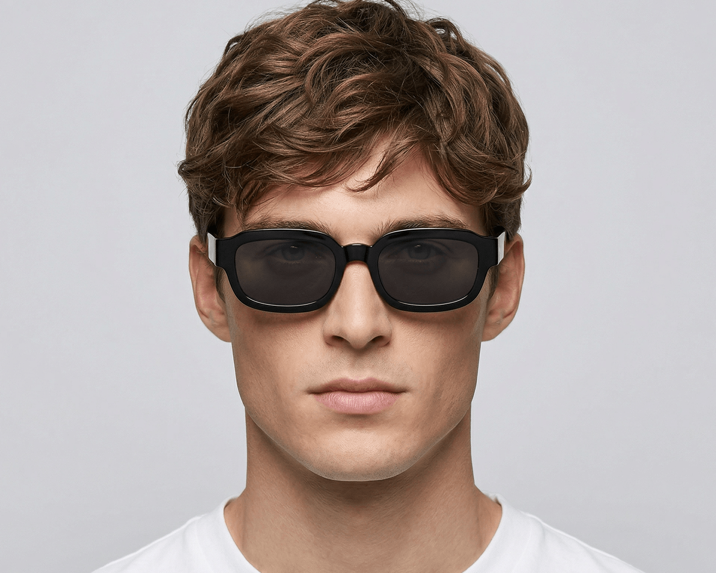 Man wearing dark sunglasses against a gray background Black