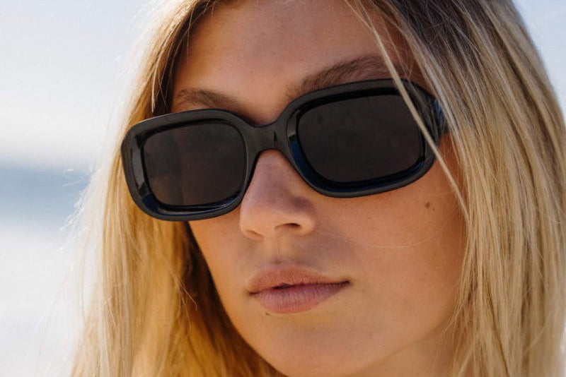 Modelis dėvi LAOS saulės akinius – juodi rėmeliai, stilingas akcentas Back