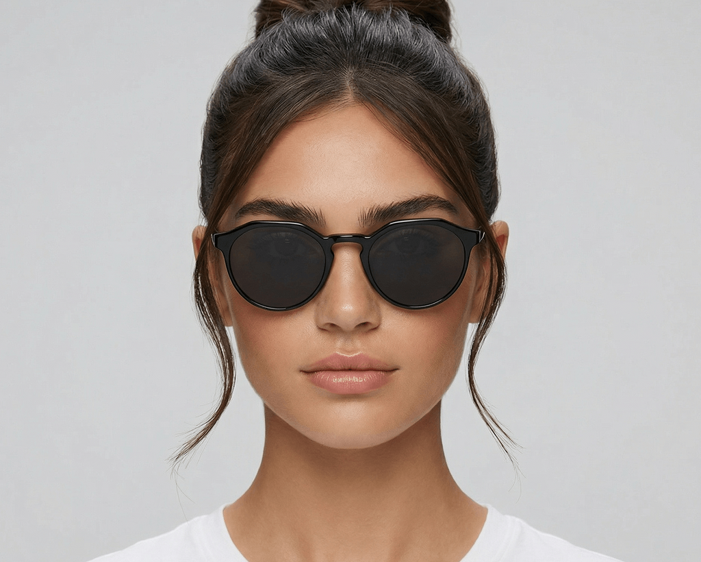 Woman wearing black sunglasses against a gray background