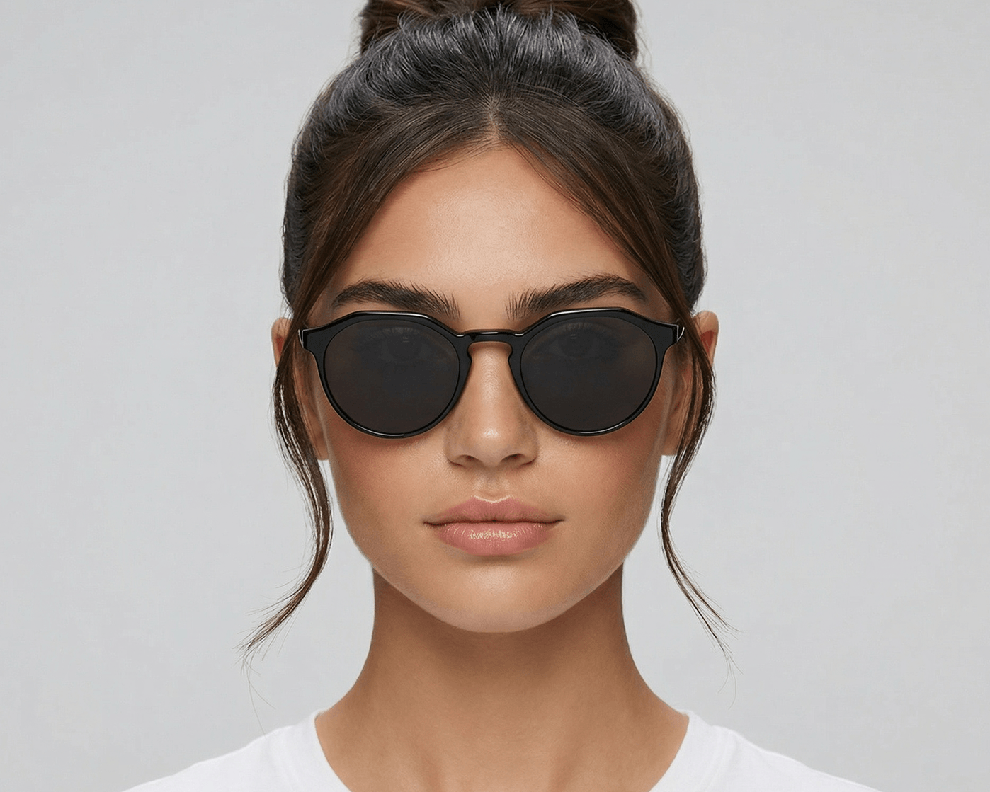 Woman wearing black sunglasses against a gray background