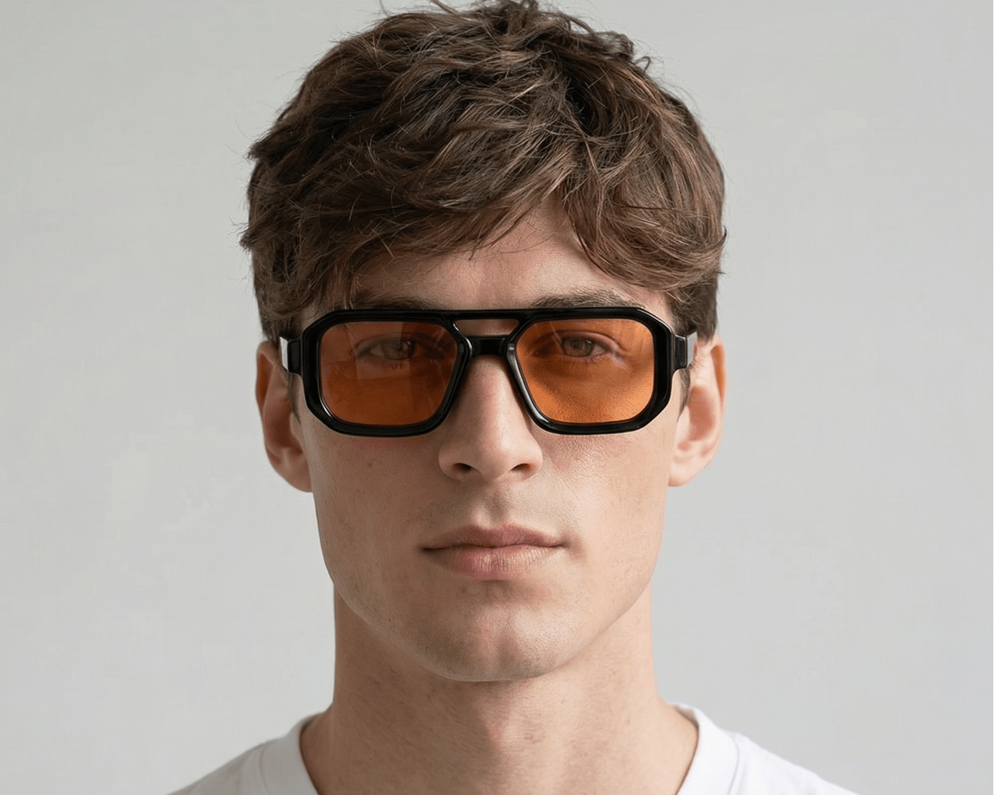 Man wearing orange-tinted sunglasses with a plain background Orange
