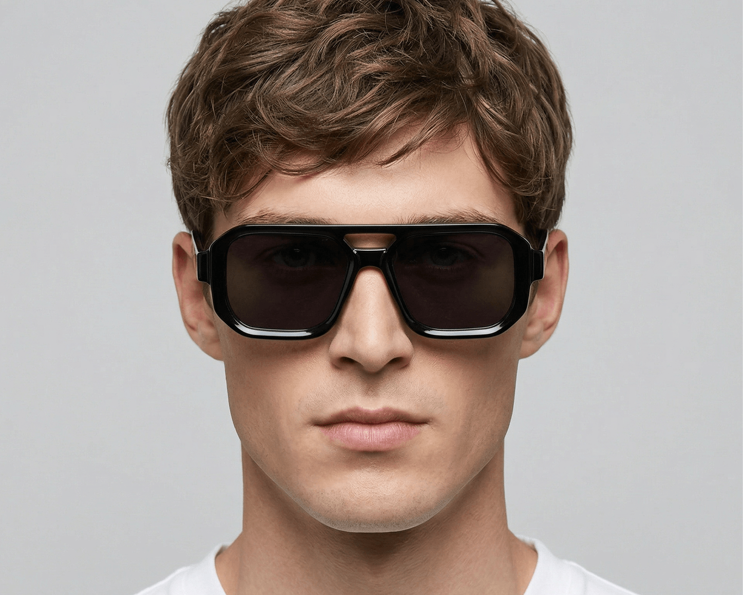Man wearing dark sunglasses against a gray background Black