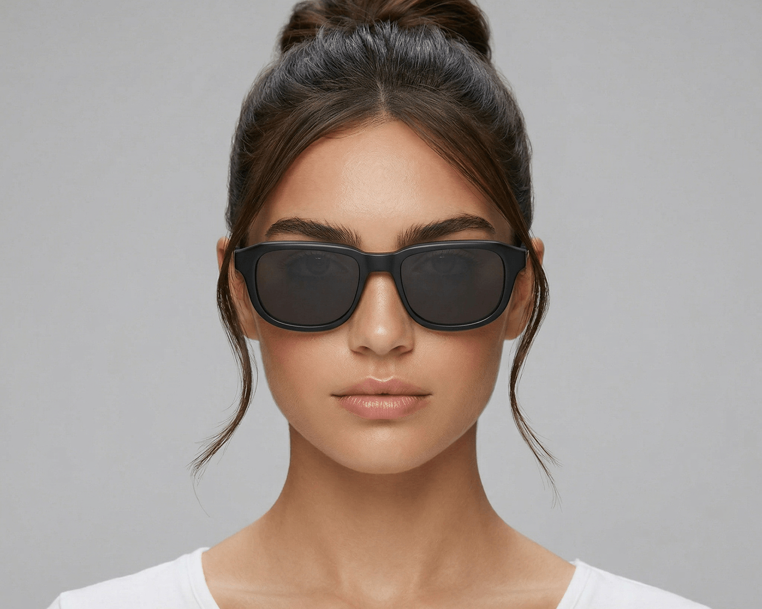Woman wearing black sunglasses against a gray background