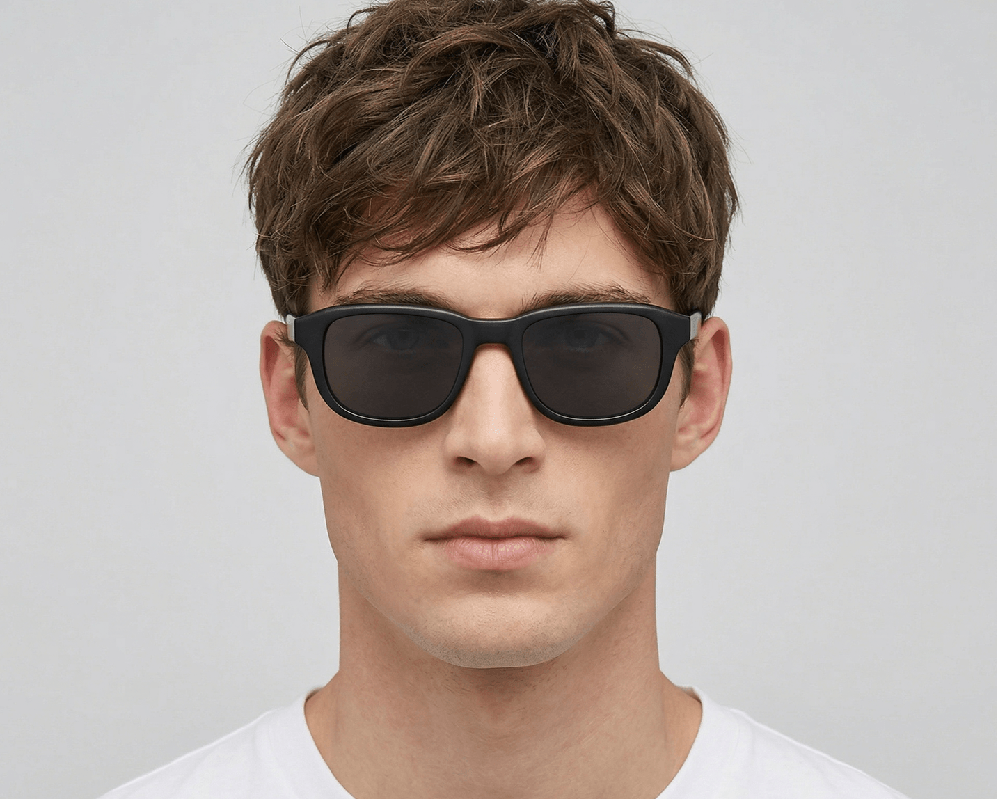 Man wearing dark sunglasses against a plain background
