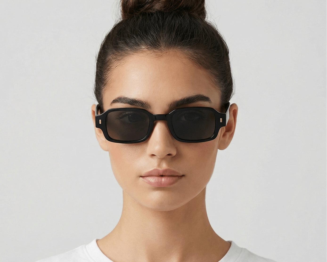Woman wearing black sunglasses against a light gray background Black