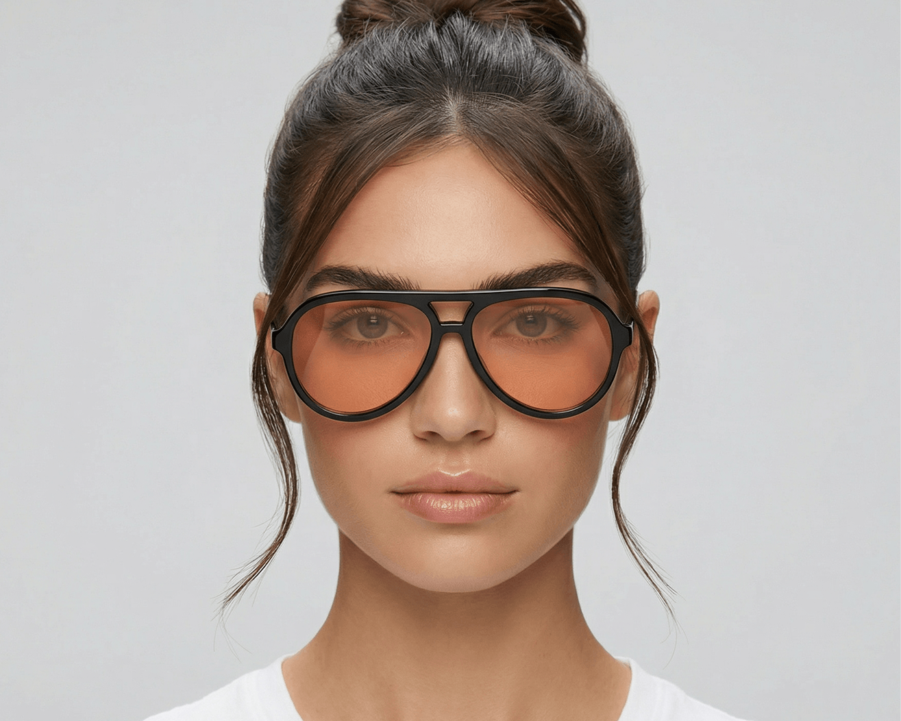 Woman wearing large black-framed sunglasses with a plain background