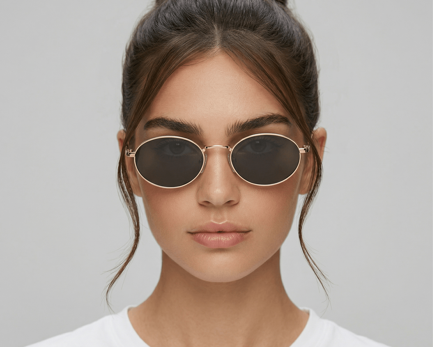 Woman wearing round sunglasses with a plain background