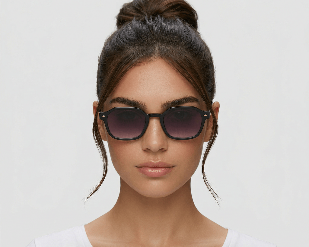 Woman wearing dark sunglasses against a plain background
