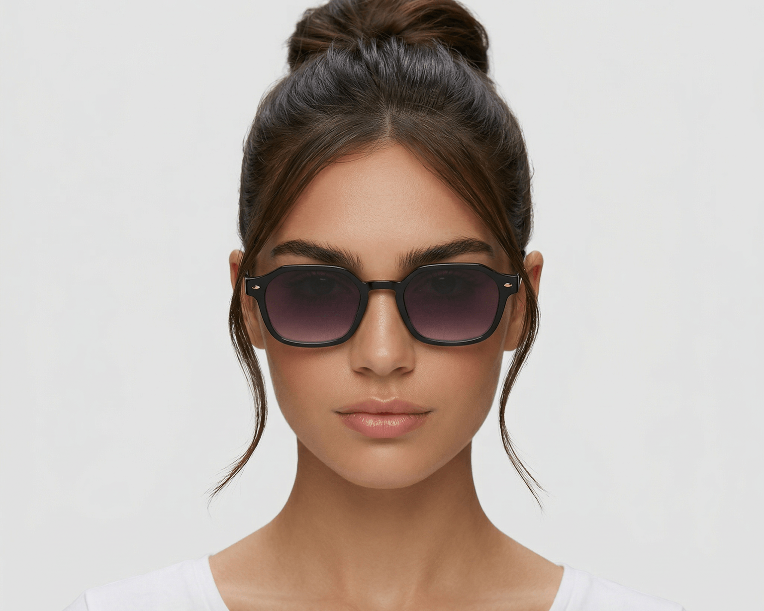 Woman wearing dark sunglasses against a plain background