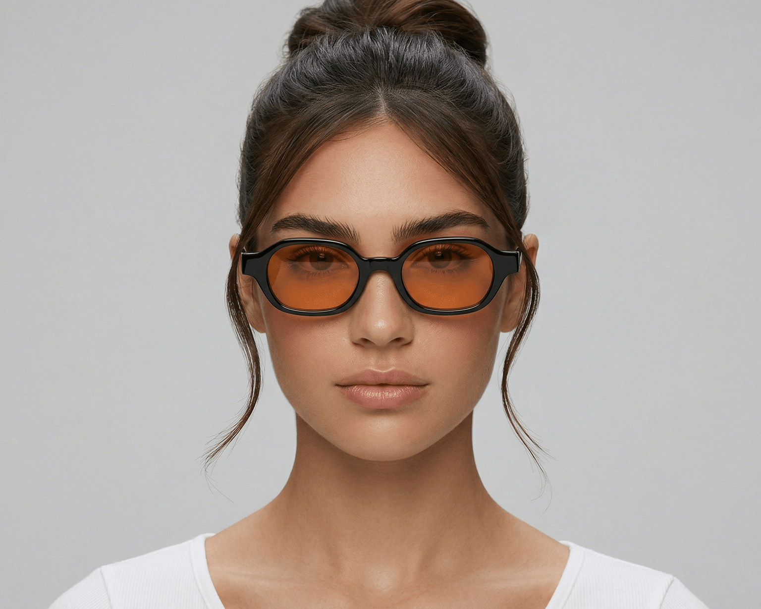 Woman wearing orange-tinted sunglasses against a gray background Orange