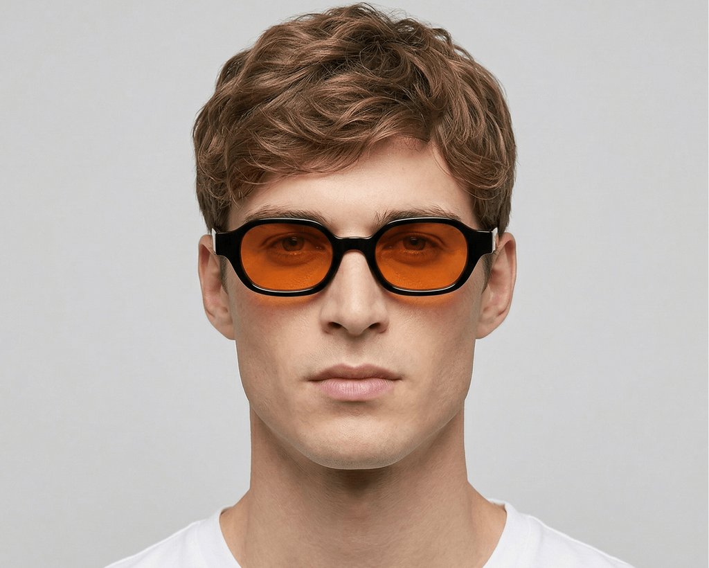 Man wearing black-framed sunglasses with orange lenses against a gray background Orange