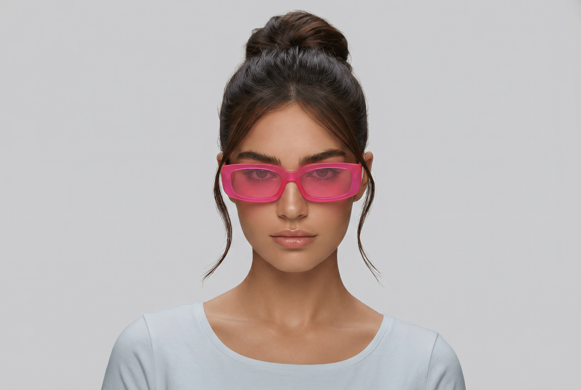 Woman wearing pink sunglasses against a gray background